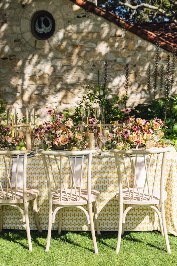 Maximalist outdoor wedding tablescape at Holman Ranch in Carmel Valley with yellow embroidered BBJ La Tavola linens, organic floral centerpieces by Amy West Floral, and vineyard garden backdrop.