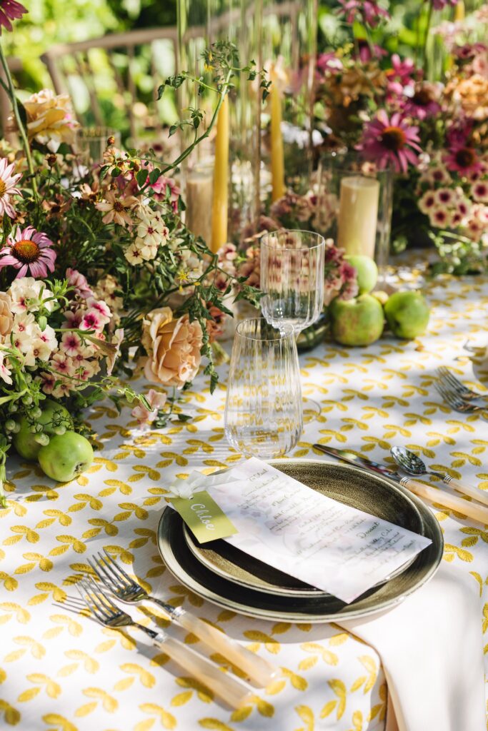 Maximalist outdoor wedding tablescape at Holman Ranch in Carmel Valley with yellow embroidered BBJ La Tavola linens, organic floral centerpieces by Amy West Floral, and vineyard garden backdrop.