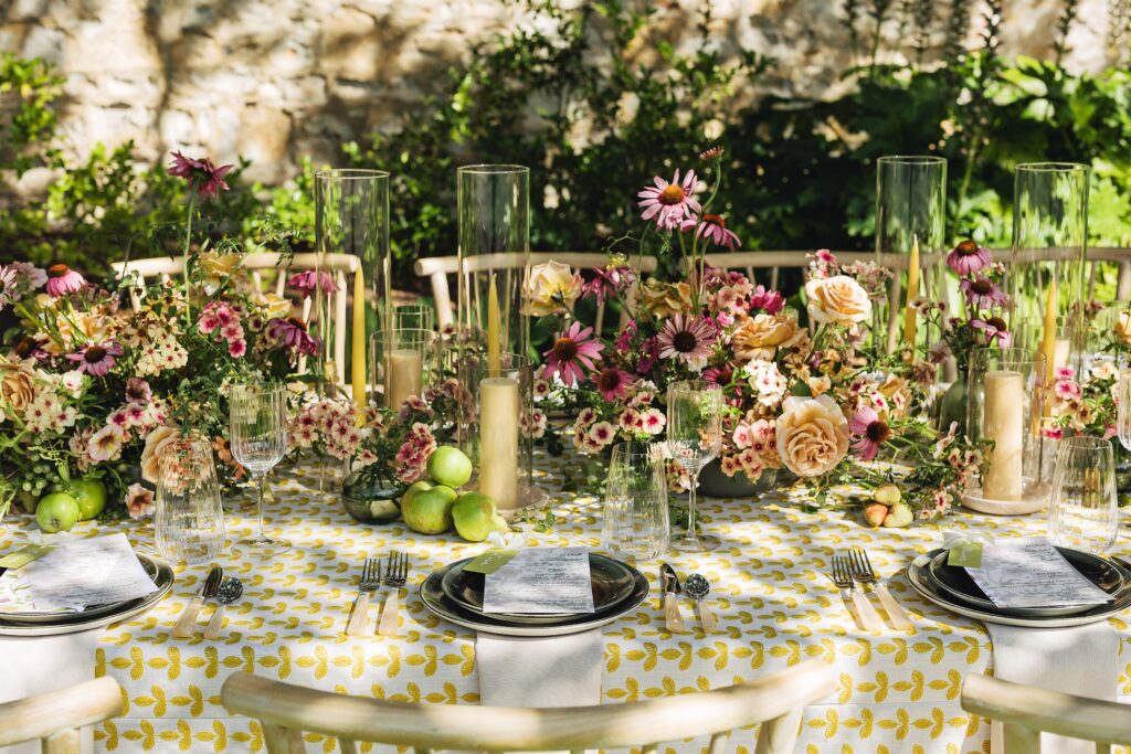 Maximalist outdoor wedding tablescape at Holman Ranch in Carmel Valley with yellow embroidered BBJ La Tavola linens, organic floral centerpieces by Amy West Floral, and vineyard garden backdrop.